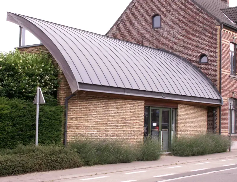 Een gebogen zinken dak op een bakstenen gebouw