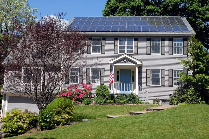 Een huis met zonnepanelen op het dak en een voortuin